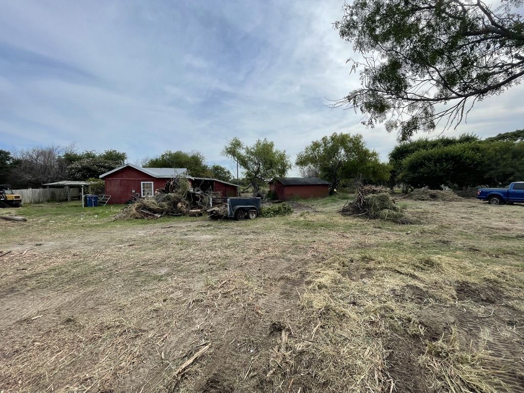 Red house and two red outbuildings on a cleared lot